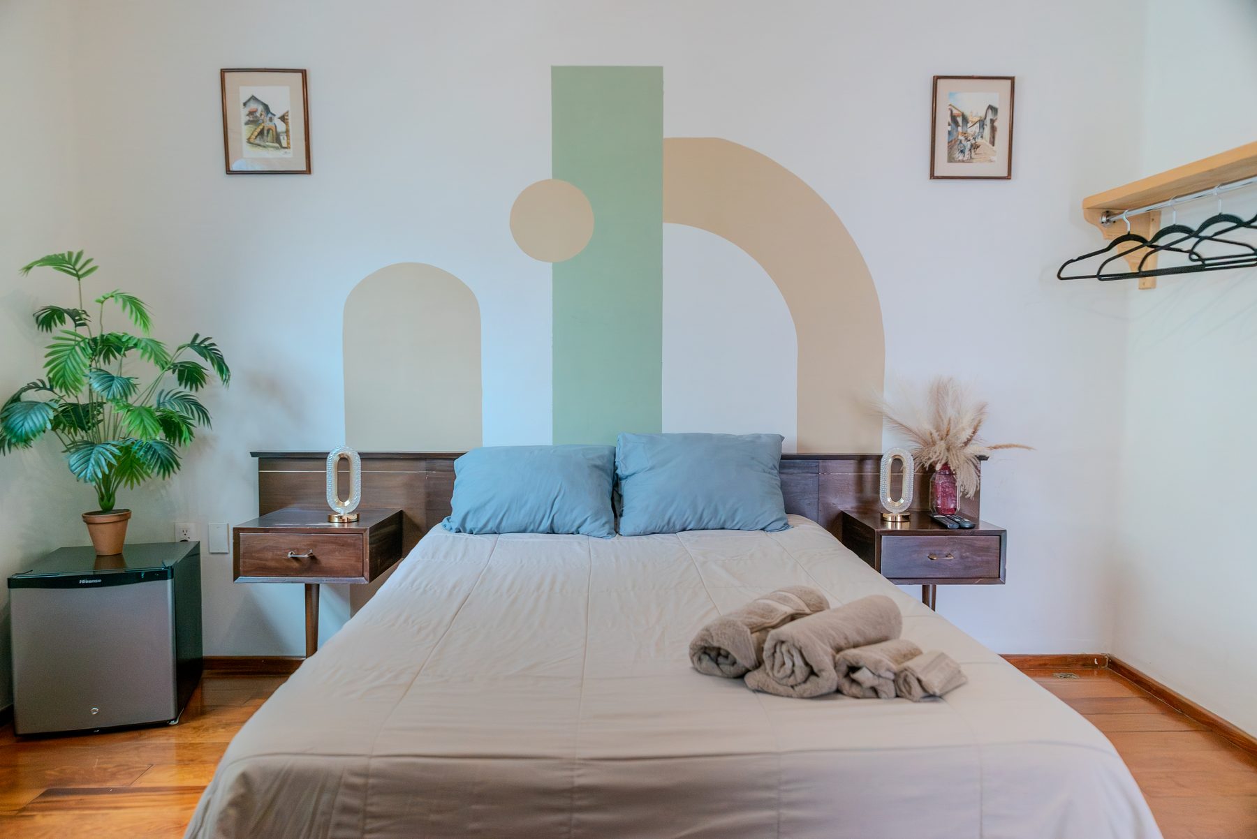 habitación de coliving con cabecera de madera y mural