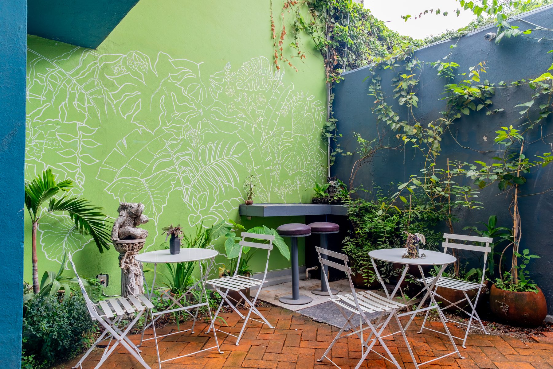 patio con mural verde y mesas bistró